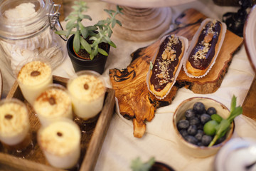 Eclairs with chocolate and wulnut on wooden tray. Sweet bar in area of wedding party