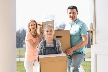 Happy family with cardboard boxes entering new home