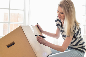 Woman labeling moving box at home