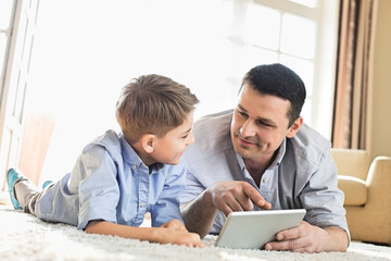 Fototapeta premium Father and son using digital table on floor at home