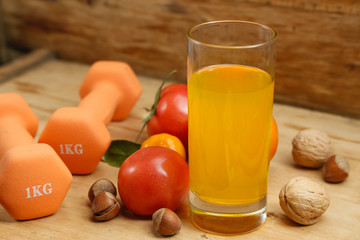 Dumbbell, orange juice, fruit and nuts on the wooden table, sport and health lifestyle concept