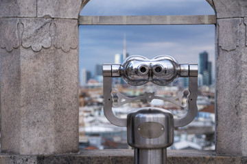 Tourist binoculars looking at out of focus city skyline