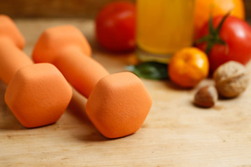 Dumbbell, orange juice, fruit and nuts on the wooden table, sport and health lifestyle concept