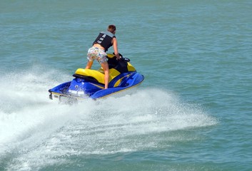 Fototapeta na wymiar Jet skier running waves while speeding across the florida intra-coastal waterway near miami beach.