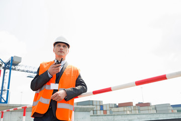 Middle-aged man using walkie-talkie in shipping yard