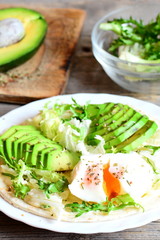 Vegetarian breakfast with a poached egg, avocado slices, chinese cabbage, lettuce, tortilla, sauce and spices. Tasty tortilla with egg and avocado recipe. Vintage wooden background. Vertical photo