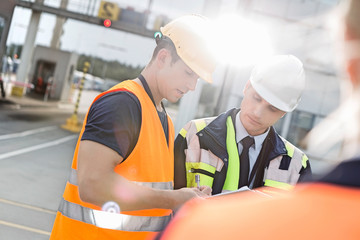 Male workers discussing over clipboard in shipping yard