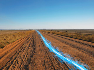 Fototapeta na wymiar Blue streak of light on dirt road against clear sky