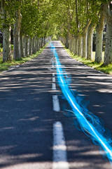 Blue streak of light on country road along trees