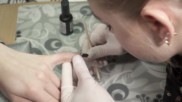 Closeup of anicure master making black manicure with the sparkles