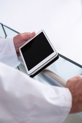 Doctor using a digital tablet in the passageway at hospital