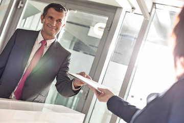 Fototapeta premium Businessman receiving document from receptionist in office
