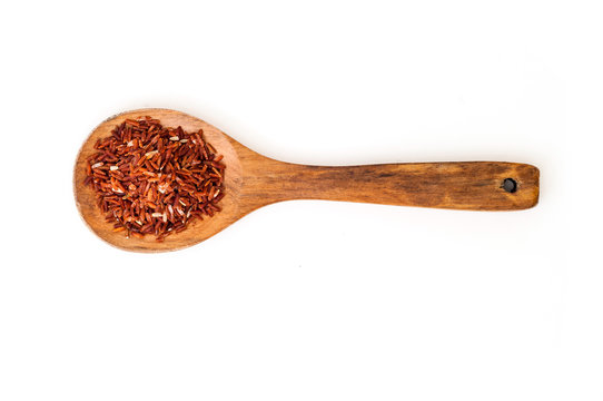 Brown raw rice on wooden spoon on white background