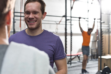 Happy man talking to male friend in crossfit gym
