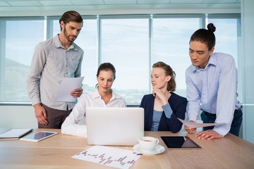 Business executives discussing over laptop in conference room