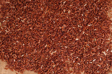 Top view to heap of raw brown rice on burlap sack material background
