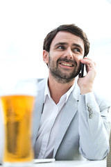 Happy businessman looking away while using mobile phone at outdoor restaurant