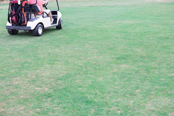 Low section of middle-aged man driving golf cart