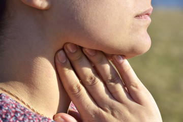 Unrecognizable woman holds her throat, sore throat