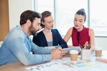 Business executives discussing over tablet 