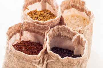 Four different kind of raw rice in open burlap sack on white background