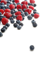 Raspberries and blueberries on white background
