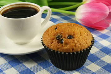 Chocolate muffins with a Cup of coffee and flowers on the table