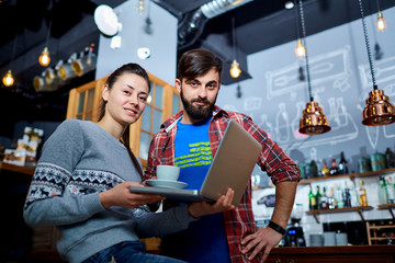 Young couple in a cafe restaurant with  laptop smiling at the table.