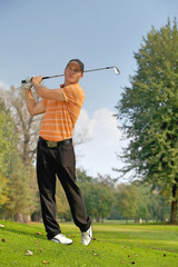 Young man swinging golf club