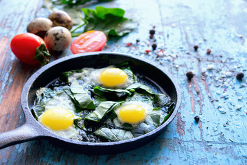 Scrambled eggs from fresh eggs tomatoes spinach hot pepper aged wooden background