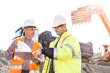 Engineers discussing over documents at construction site