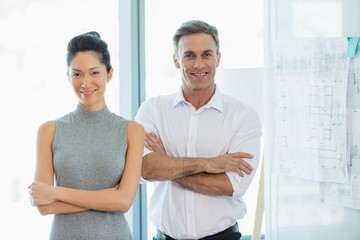 Smiling architects standing with arms crossed in office