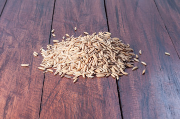 Heap of unpolished raw rice on wooden table