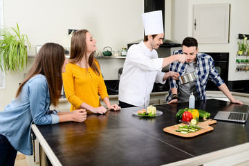 professional personal chef cook in customer's private kitchen house giving a cooking lesson to young people at home