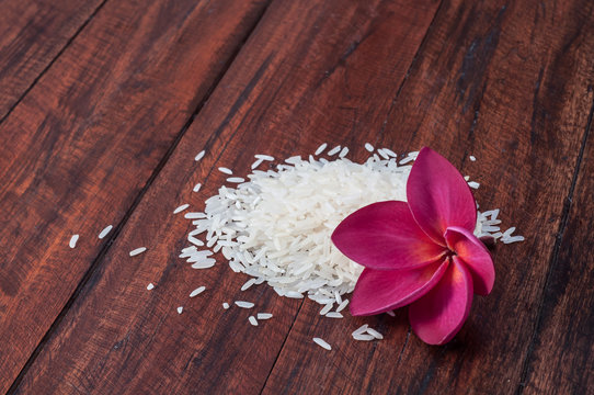 White Jasmine rice with pink plumeria flower on dark wooden table