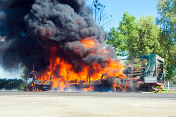 truck in fire with black smoke on the road