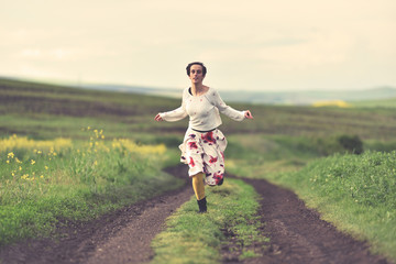 Fototapeta premium Woman in white skirt running on a countryside road