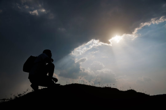 Silhouette of man sitting and sky with sunlight