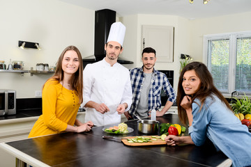 professional personal chef cook in customer's private kitchen house giving a cooking lesson to young people at home
