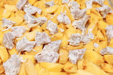 Sliced potatoes with meat, raw on a baking sheet