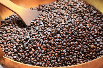 Traditional coffee beans roasting in metal basin with spatula as background or print card.