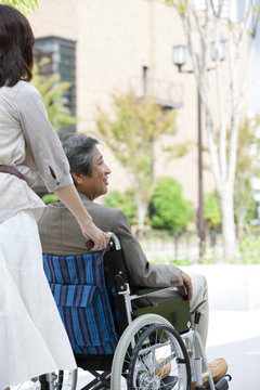 Mature woman pushing senior man on wheelchair