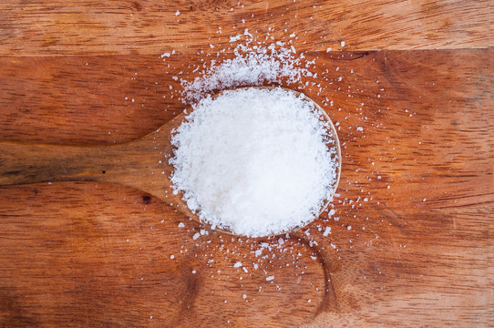 Salt or sweet sugar in wooden spoon on wood desk