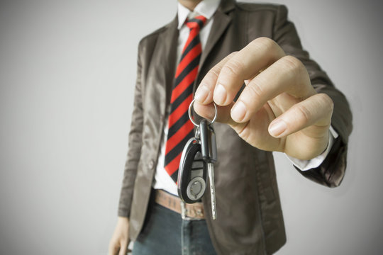 Man's hand showing Car Key,Successful businessman offering a car key