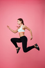 Fototapeta na wymiar Woman in sport clothing pretends running in air jumping high 
