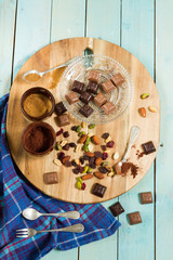 Chocolate bars. On wooden board, glass plate, coffee and milk.