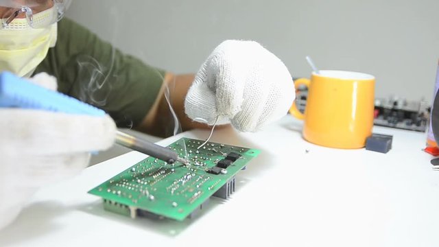 Technician is soldering to the electronic print circuit board 