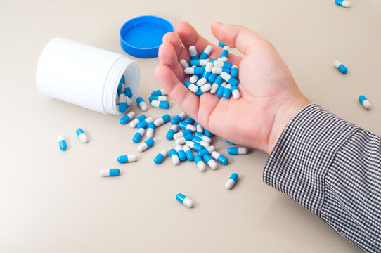 Man holds heap of blue medical pills for suicide