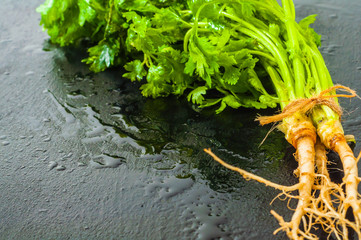 Green fresh parsley on black board kitchen surface with water drop