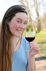 Beautiful young woman drinking wine in the park.